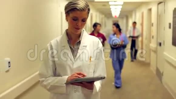 医生使用数码平板电脑沿医院走廊行走视频的预览图
