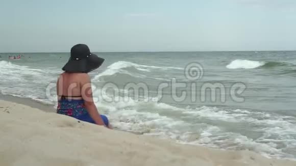 在海滩上戴帽子穿蓝色裙子的女人视频的预览图