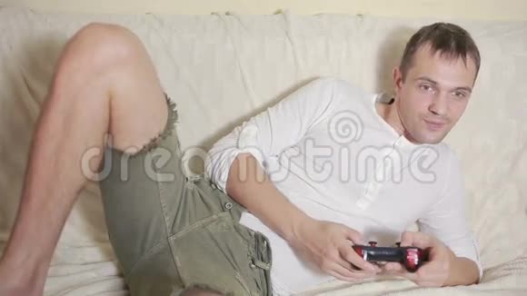 坐在沙发上的男人在黑暗的房间里玩电子游戏视频的预览图