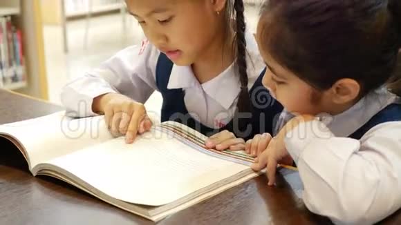 在图书馆里有统一阅读书籍的亚洲小学生一起倾斜相机视频的预览图