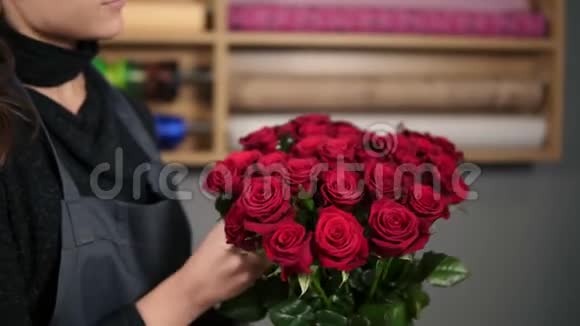 关注一束红玫瑰年轻迷人的女性花店在花店里布置一束美丽的红玫瑰视频的预览图