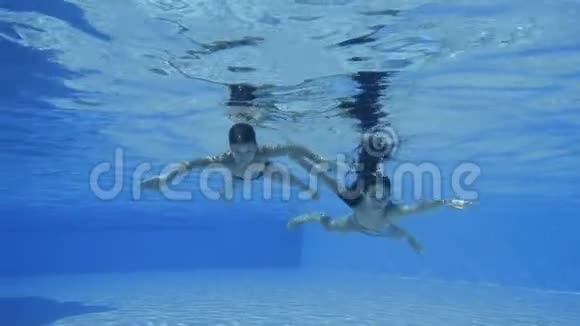 男孩和女孩在游泳池里潜水慢动作视频的预览图