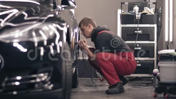 用抛光泥抛光汽车穿红西装的工人在清洗一辆黑色昂贵的汽车视频的预览图