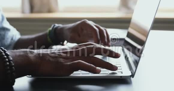美国黑人男性用户在桌旁的笔记本电脑上打字特写视频的预览图