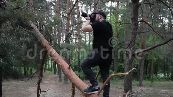 一个在森林里拿着摄像机的黑衣人视频的预览图
