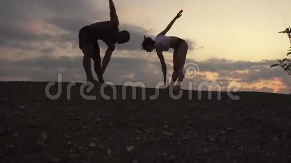 运动混合种族夫妇的剪影一起伸展在岩石山的背景体育健身理念视频的预览图