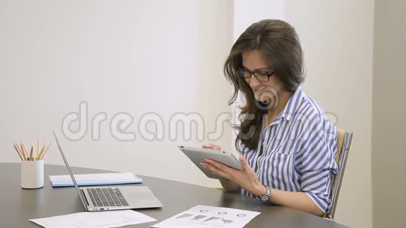 女员工手里拿着平板电脑坐在现代办公室里视频的预览图