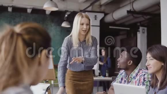 漂亮的金发女经理给多民族团队指路现代时髦办公室的创意商务会议视频的预览图