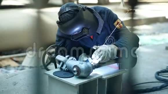 钢结构制造车间带防护面罩焊接inox元件的工业工人视频的预览图