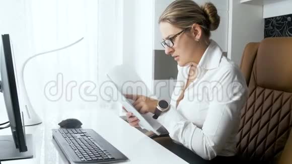 年轻优雅的女商人在办公室用台式电脑阅读文件的4k镜头视频的预览图