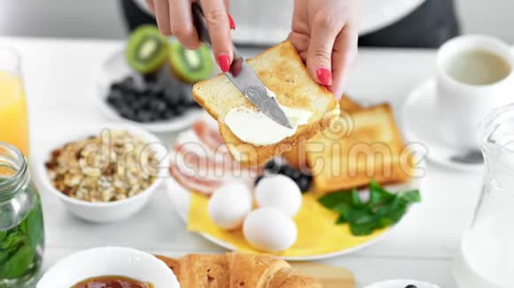 特写女性手在油炸面包烤面包上涂黄油用刀享受早餐食物视频的预览图