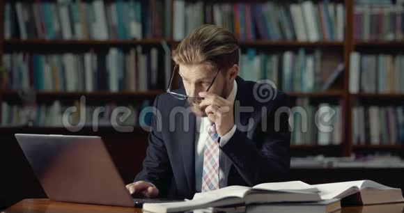有胡子的男性图书馆里有笔记本电脑视频的预览图