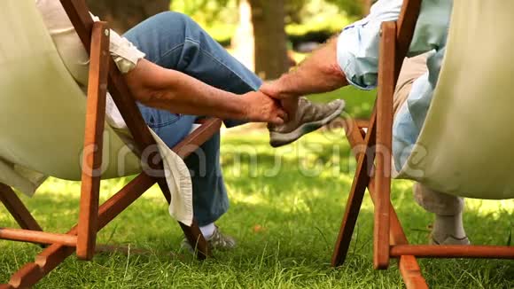一对退休夫妇手牵手坐在躺椅上视频的预览图