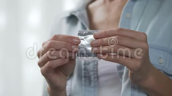 从包裹里拿出避孕套在镜头前展示安全性行为视频的预览图