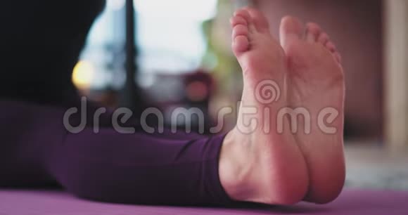 一位金发女郎在家练习瑜伽在运动垫上伸展身体穿着舒适的衣服的肖像视频的预览图