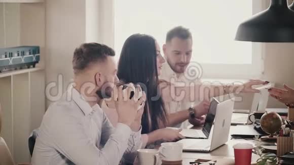 快乐年轻的欧洲商人坐在桌子旁与笔记本电脑一起工作在现代健康的办公室慢动作视频的预览图