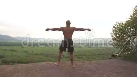 美籍非洲裔健美运动员在早上的户外训练中完美的身体伸展在山顶上视频的预览图