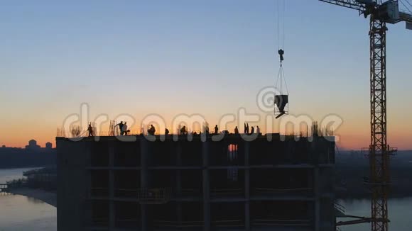 日落时用吊车和工人对施工现场进行空中拍摄视频的预览图