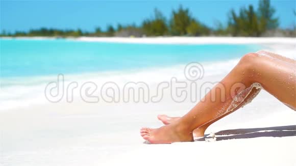 在白色的热带海滩上雌性苗条的晒黑腿流动电视视频的预览图