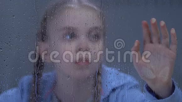 可爱的孤独的青春期女孩看着窗外的雨被雷雨吓坏了视频的预览图