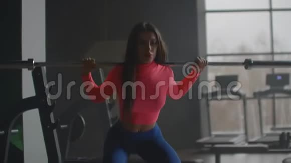 女孩蹲在健身房里用杠铃视频的预览图