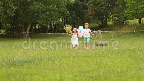 小男孩牵着女孩的手他们一起沿着草坪跑慢动作视频的预览图
