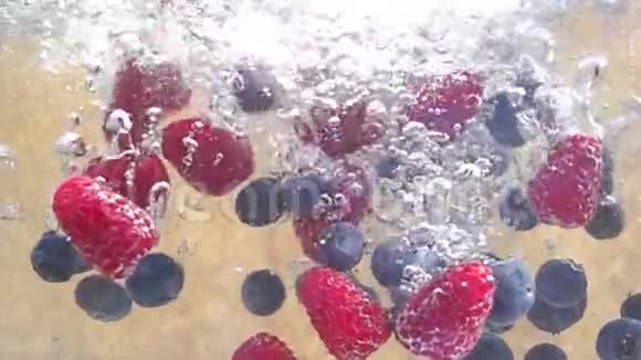 蓝莓和覆盆子沉到水里的慢动作视频视频的预览图