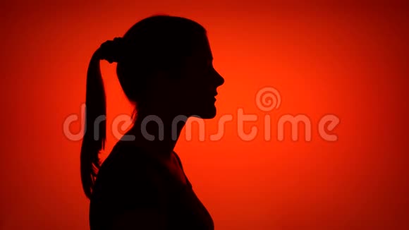 年轻女子在红色背景上做沉默手势的剪影神秘和保密的概念视频的预览图