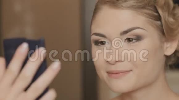 化妆的女孩对着镜子看自己视频的预览图