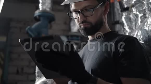 戴头盔的技术员在装有平板电脑的锅炉房工作视频的预览图