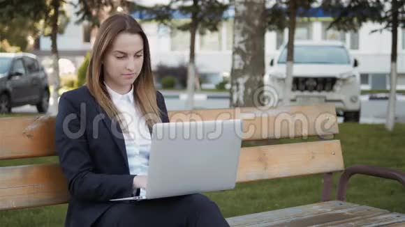 年轻漂亮的商务女性使用笔记本电脑坐在户外视频的预览图