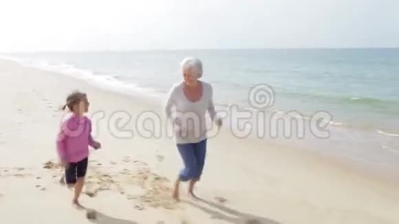 祖母和孙女一起沿着海滩奔跑视频的预览图