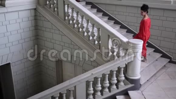 穿着优雅的红色高跟鞋的歌手爬上漂亮大厅的大楼梯视频的预览图