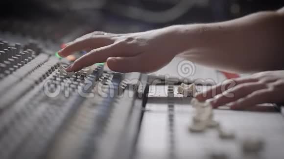 侧视镜头的音乐家工作的音频混合控制台在音乐工作室视频的预览图