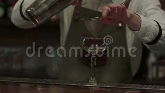 专家酒吧老板把准备好的摇床鸡尾酒倒入玻璃杯中然后把它放在夜总会的餐巾上视频的预览图