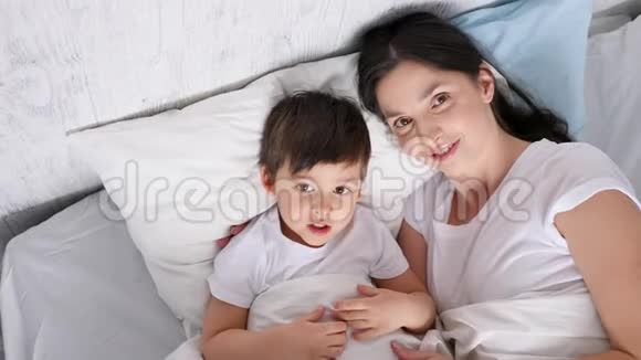 母亲和儿子躺在房间里的一张白床上视频的预览图