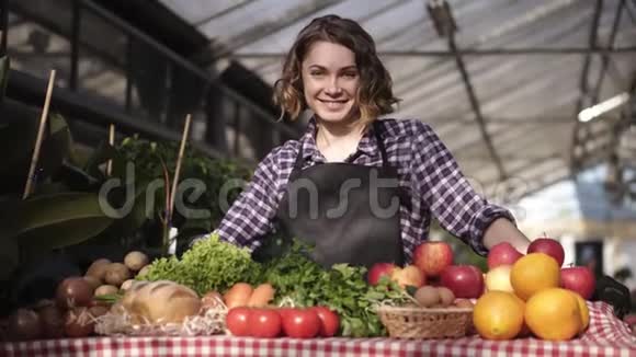 一幅美丽短发微笑的女农民在农贸市场出售有机食品的画像微笑着看着镜头视频的预览图