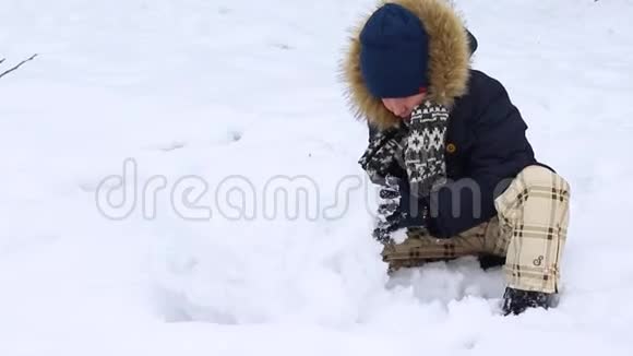 小男孩在雪地雪人上雕刻视频的预览图