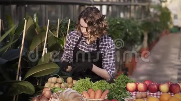 戴着黑手套的漂亮女农民在农场市场上摆放有机食品的肖像站在宽敞的室内视频的预览图