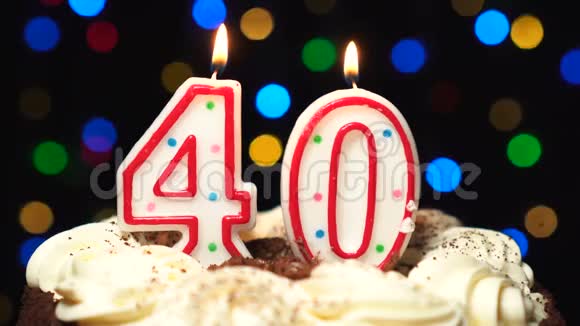 在蛋糕上面的40号40岁生日蜡烛燃烧在最后吹灭彩色模糊背景视频的预览图
