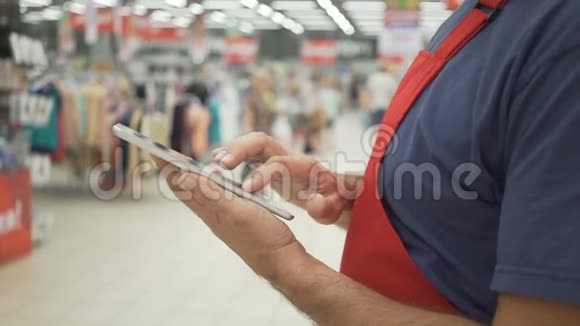 穿红色围裙的销售人员使用的数字平板电脑背景是商店视频的预览图