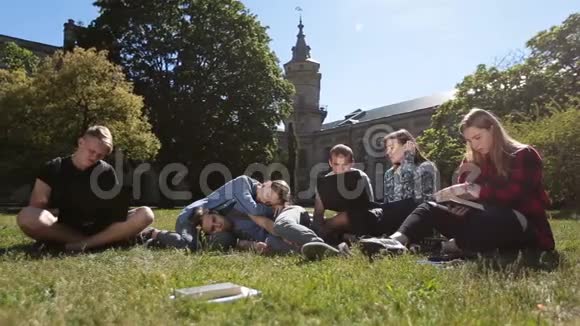 一群疲惫的学生在公园草坪学习视频的预览图