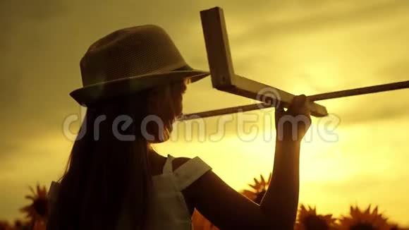 戴帽子的女孩玩木飞机快乐的孩子在日落时在向日葵田玩玩具飞机在视频的预览图