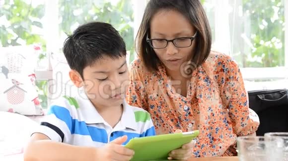 一个亚洲孩子和妈妈在电子平板上用一些东西来吸引孩子的注意力视频的预览图