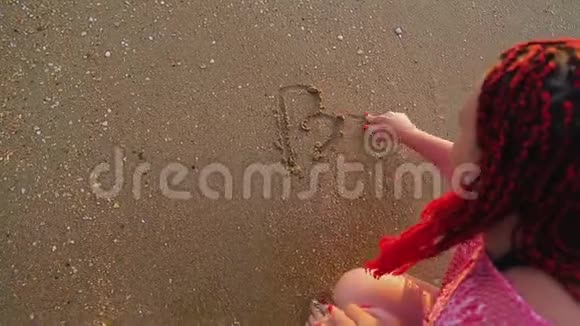 一个女人在沙滩上写海滩这个词视频的预览图