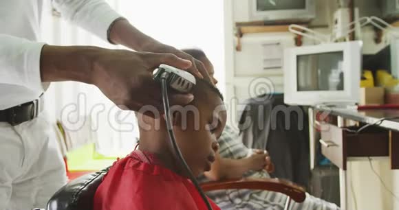 非洲男人剪非洲男孩的头发视频的预览图