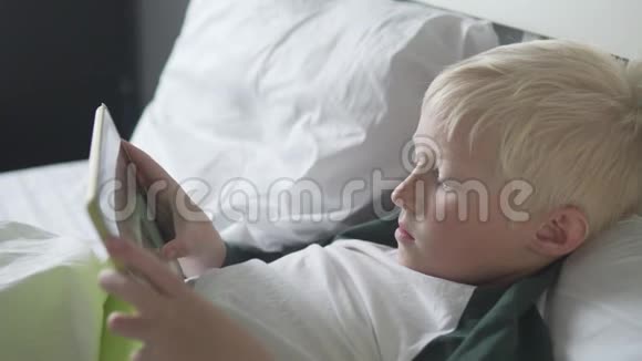 漂亮的金发男孩躺在床上视频的预览图