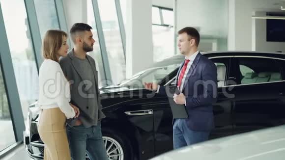 有兴趣的一对男女正在和汽车经销商经理谈豪华汽车的事视频的预览图