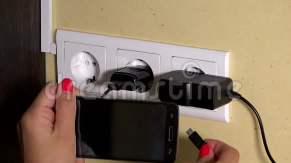 女性手把智能手机插到墙上充电器手里视频的预览图