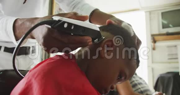 非洲男人剪非洲男孩的头发视频的预览图